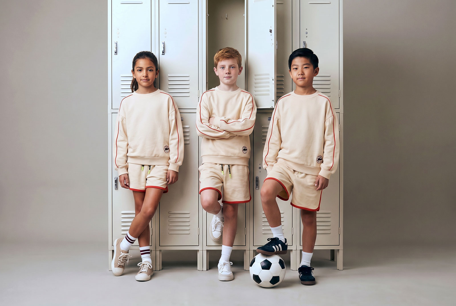 Niños con equipaciones de fútbol ROOTS junto a taquillas
